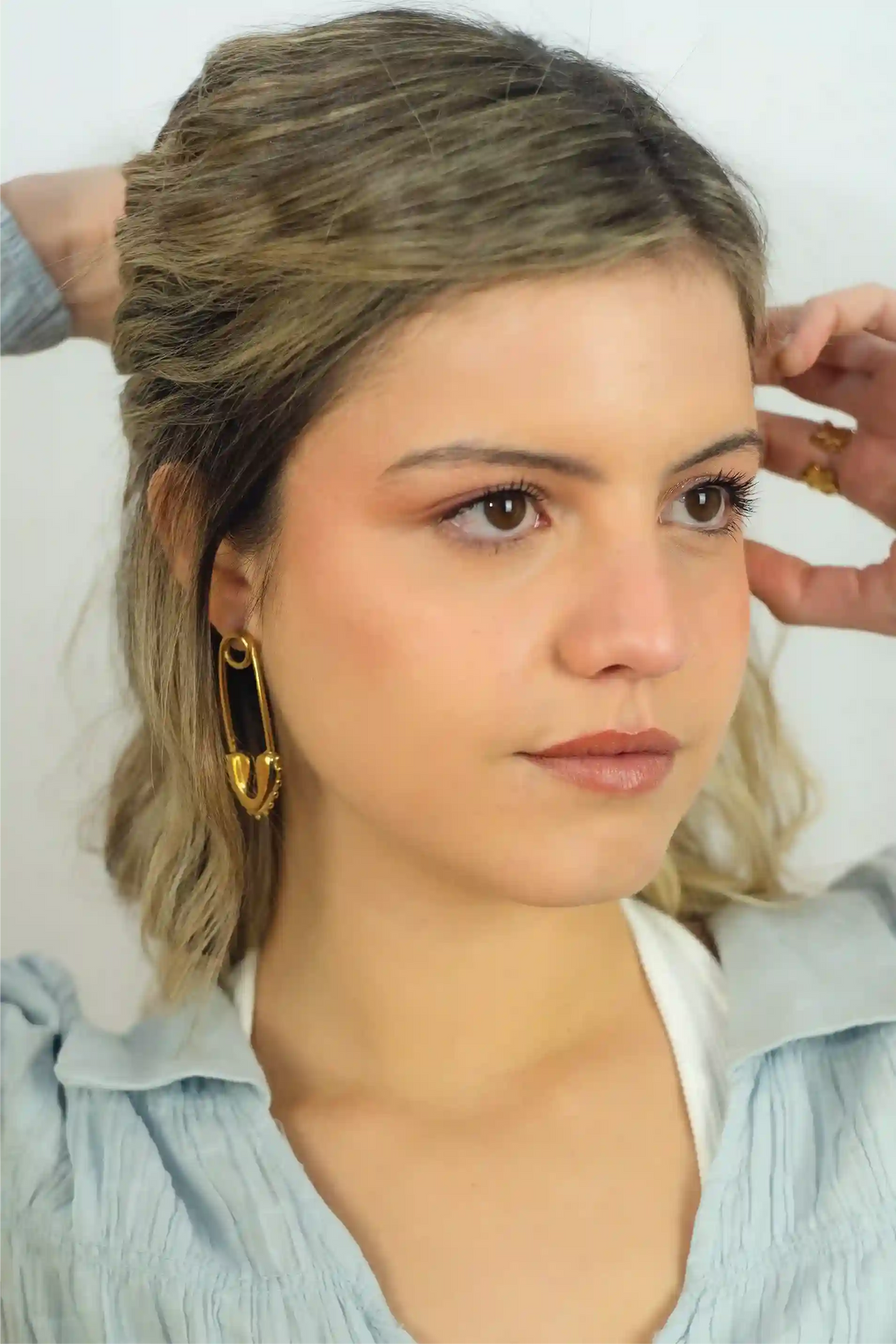 Woman with styled hair and earrings against a neutral background