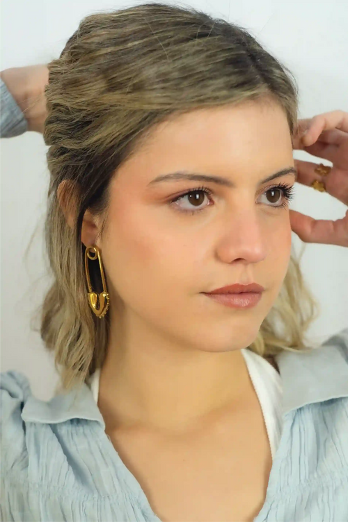 Woman with styled hair and earrings against a neutral background