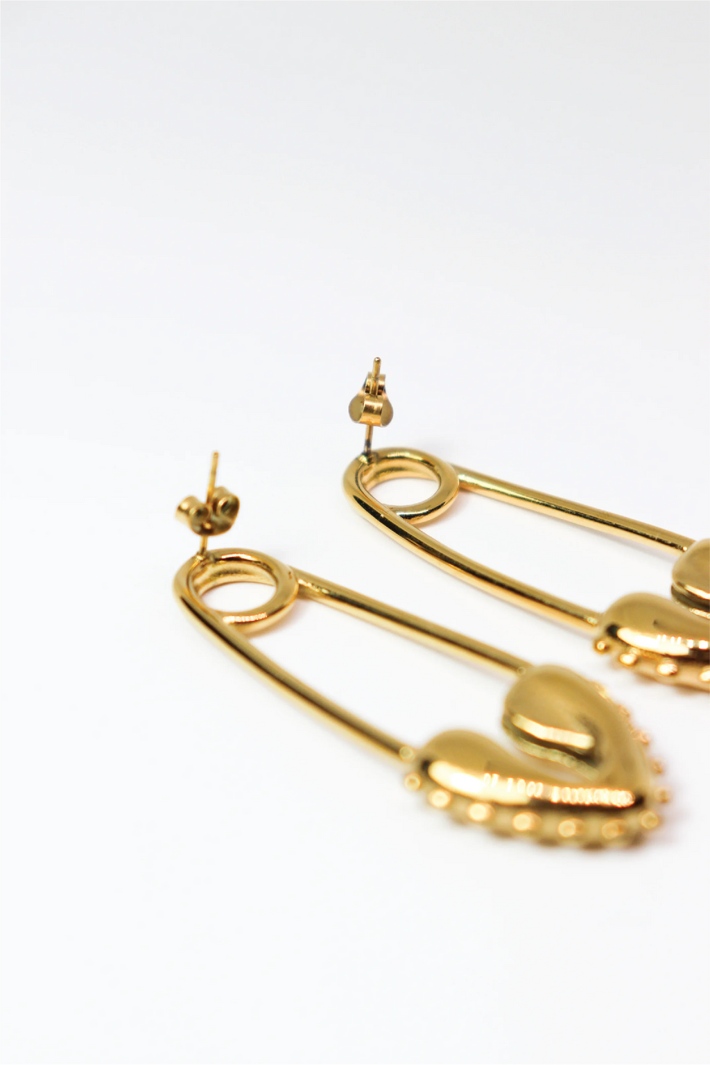 Gold safety pin earrings on a white background