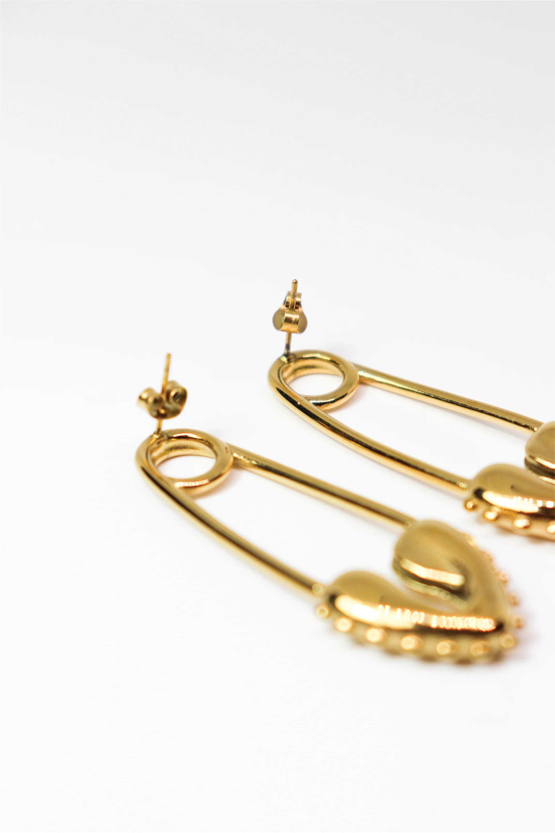 Gold safety pin earrings on a white background