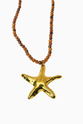 Gold starfish pendant on a beaded necklace against a white background